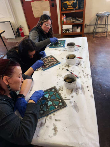 Three women grouting a personal mosaic project.