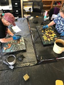 Two women grouting a personal mosaic project